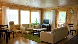 Una sala de estar acogedora con paredes de madera, un sofá, una mesa de centro y un televisor.