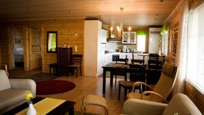 Acogedor interior de cabaña de madera con sala de estar, comedor y cocina.