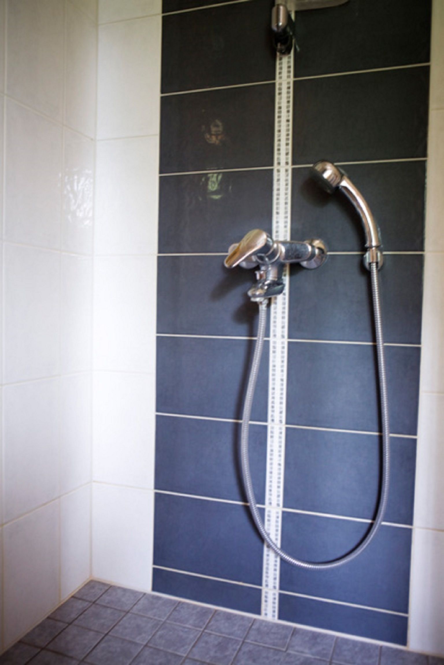 A bathroom with a shower, tiled walls, and a measuring scale.