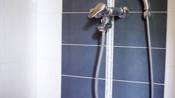 A bathroom with a shower, tiled walls, and a measuring scale.