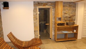 A room with a stone wall, wooden bench, and a wooden shelf with a bowl. - Rommelehof (Gutach)