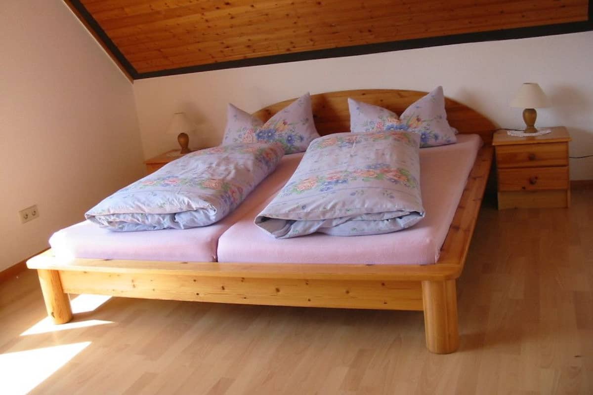 A wooden bed with floral bedding in a room with a sloped ceiling.