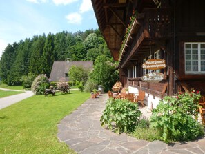 A rustic wooden building with a stone pathway leading to a seating area. - Rommelehof (Gutach)