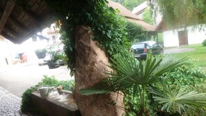 A stone pathway leading to a building with a large rock and a potted plant. - Rommelehof (Gutach)