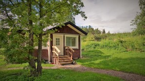 A small wooden cabin with a porch and a set of stairs leading to the entrance. - Salkolahti Vehmaanpirtti (Orivesi)
