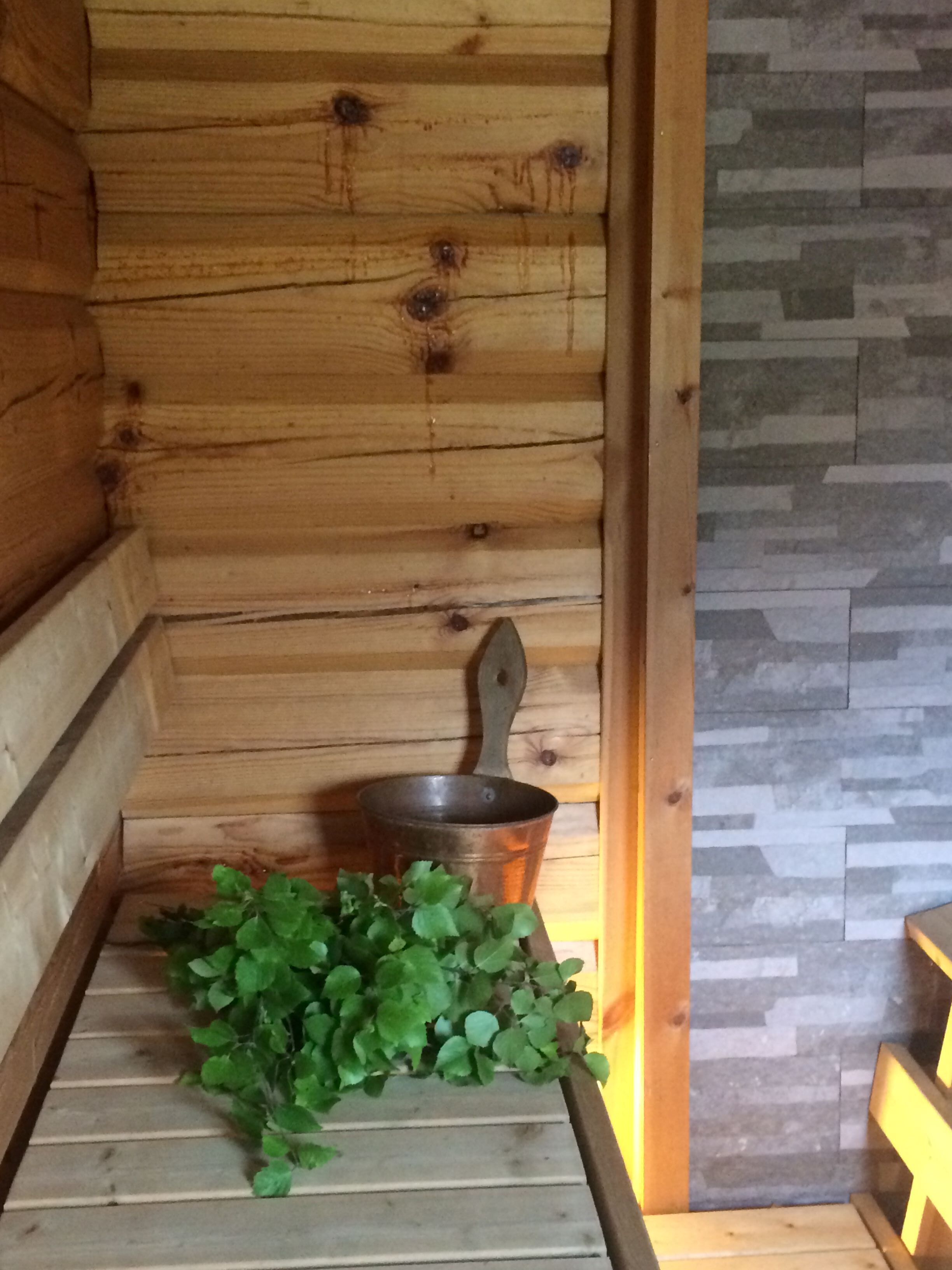 Un interior de madera con diseño rústico, que incluye un banco de madera y una olla de metal.