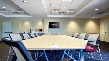 A conference room with a long table, chairs, and a television screen displaying "TOWNEPLACE SUITES".