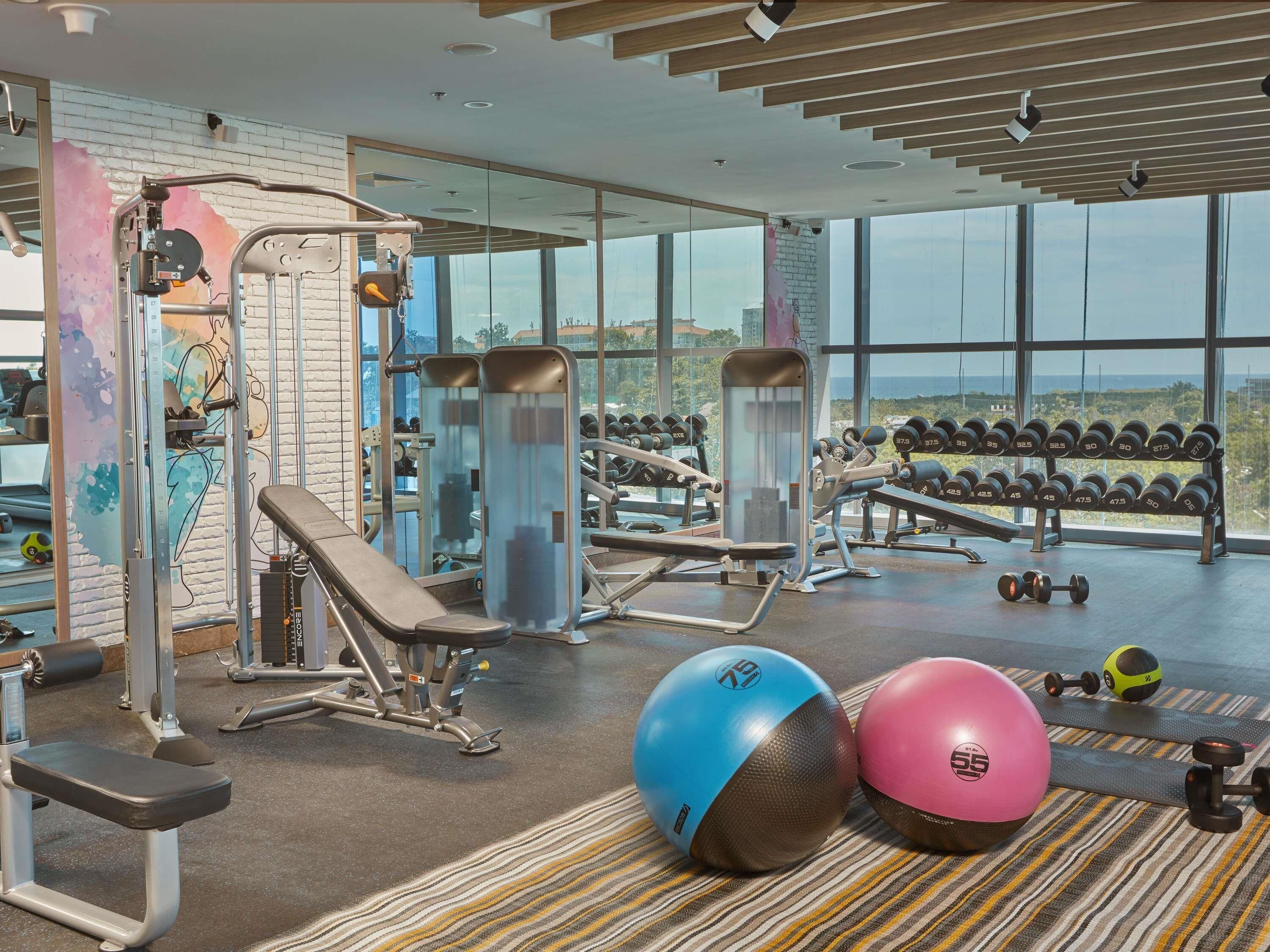 Un gimnasio con equipo de ejercicio, una banca, mancuernas y pelotas de gimnasia.