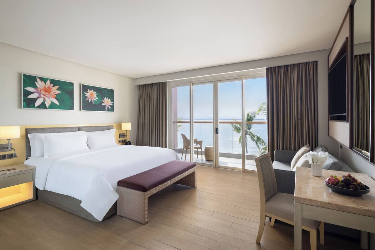 Ein Hotelzimmer mit einem großen Bett, einem Essbereich und einem Balkon mit Blick.