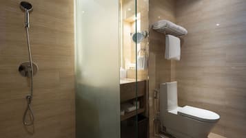 A modern bathroom with a glass-enclosed shower, a toilet, and a glass partition.