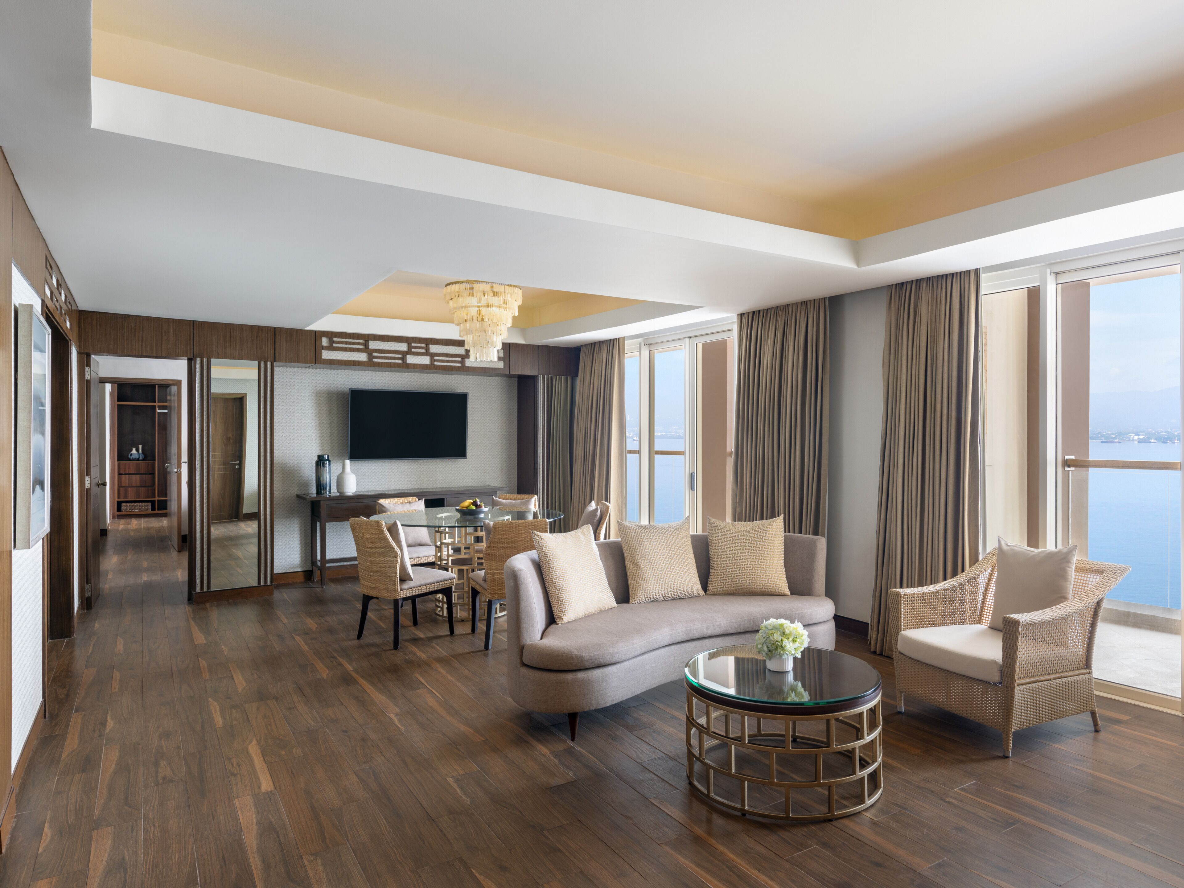 Habitación de hotel moderna con zona de comedor, un sofá, una mesa redonda y un ventanal con vistas.