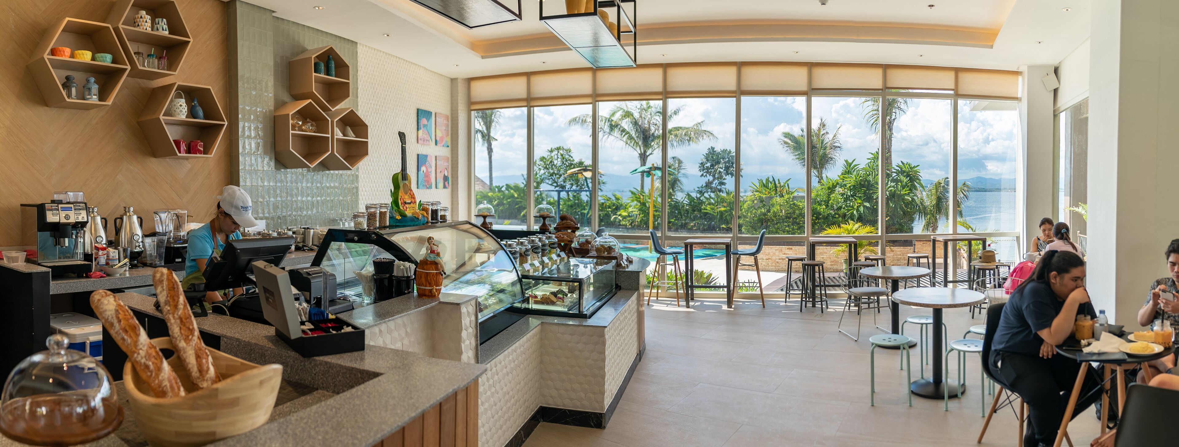Un café moderno con mostrador, zona de estar y amplios ventanales con vistas panorámicas.