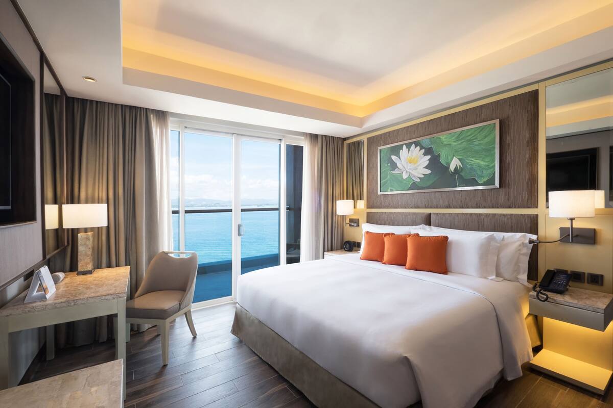 Ein Hotelzimmer mit einem großen Bett, einem Schreibtisch, einem Stuhl, einem Telefon und einem Bild an der Wand.