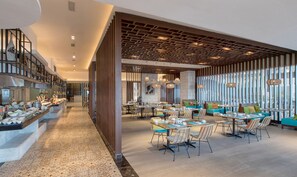 Un restaurante moderno con una barra larga, varias mesas para comer y sillas.