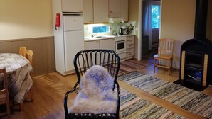 A cozy kitchen with wooden cabinets, a stove, and a dining area with a table and chairs. - Salkolahti Tikkamaki (Orivesi)