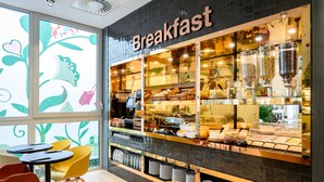 A breakfast area with a counter displaying various food items and a selection of chairs and tables.