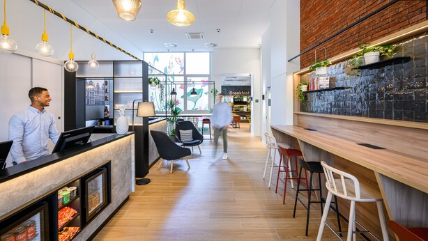 A modern interior with a reception desk, seating area, and a bar.