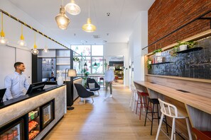 A modern interior with a reception desk, seating area, and a bar. - B&B HOTEL Brussels Centre Gare du Midi (Brussels)