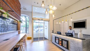 A modern bar area with wooden flooring, a brick accent wall, and hanging pendant lights.