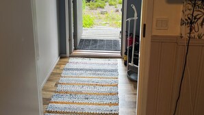 A hallway leading to a door with a view of a lake and forest. - Salkolahti Huvikumpu (Orivesi)