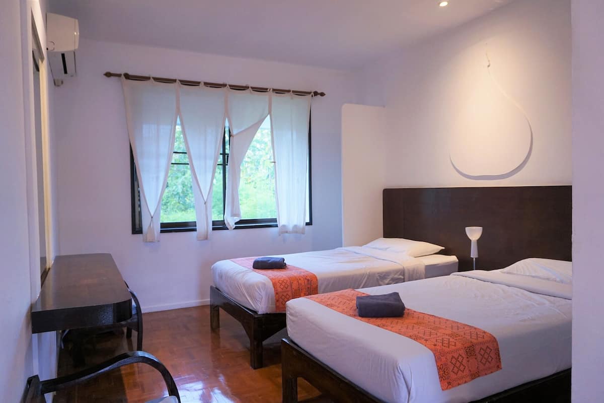 A hotel room with two beds, a desk, and a chair.