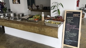 A buffet counter with various food items and a blackboard menu listing breakfast, lunch, dinner, and night break options. - Amaravati Wellness Center and Resort (Mae Rim)