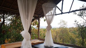 A room with a bed, a bench, and a view of the forest. - Amaravati Wellness Center and Resort (Mae Rim)