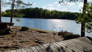Eine Holzterrasse mit Blick auf einen stillen See, im Hintergrund ein Wald.