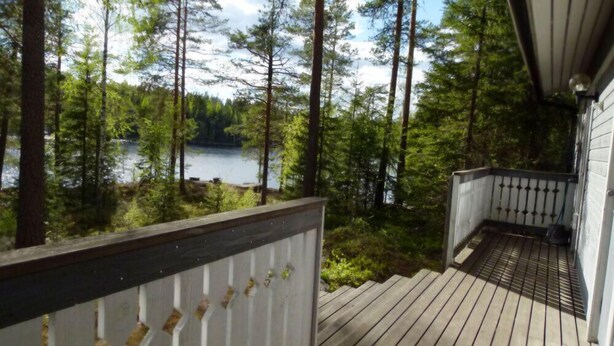 Eine Holzterrasse mit Geländer, mit Blick auf einen See und einen Wald.