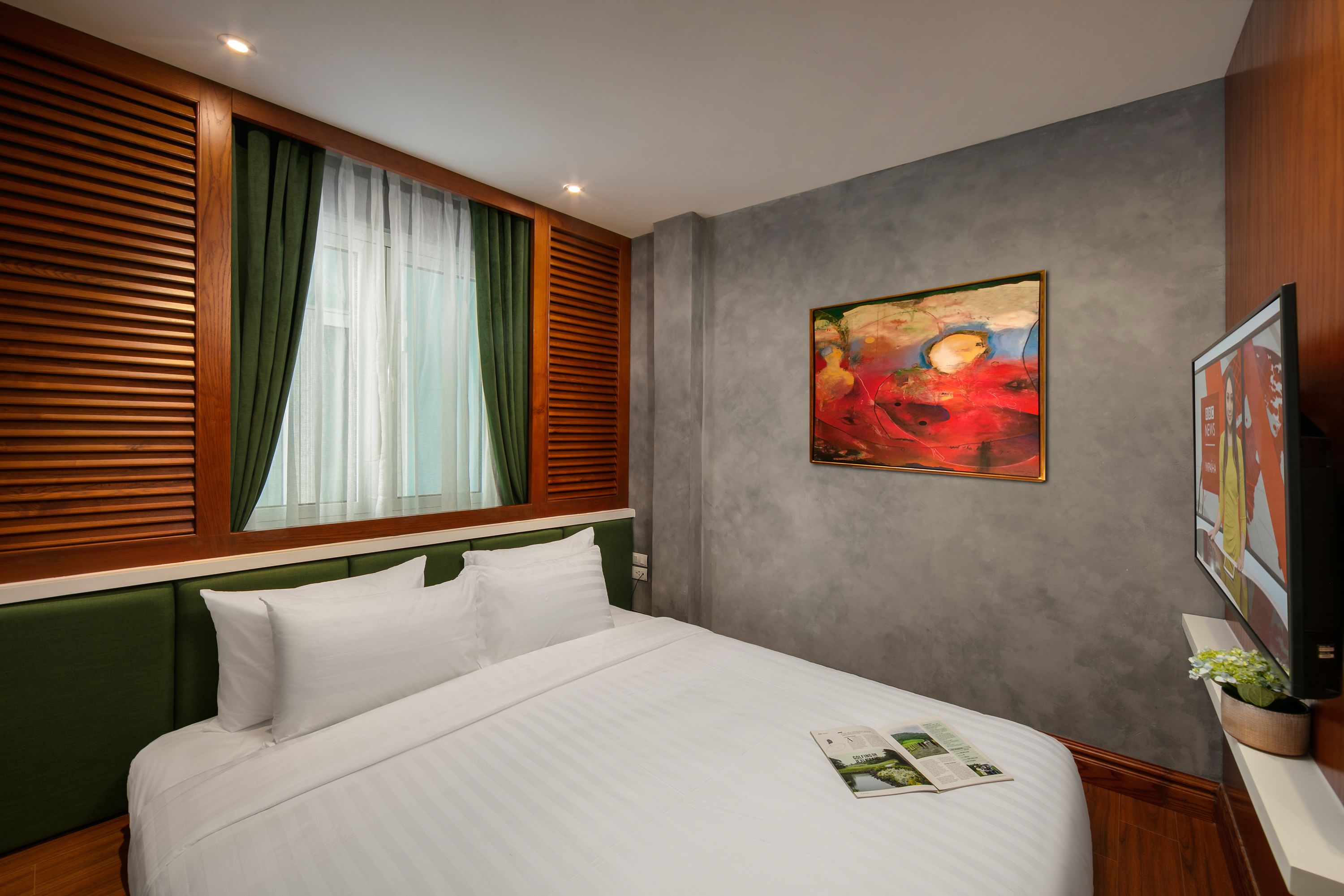 Una habitación de hotel con una cama, un cuadro y un televisor.