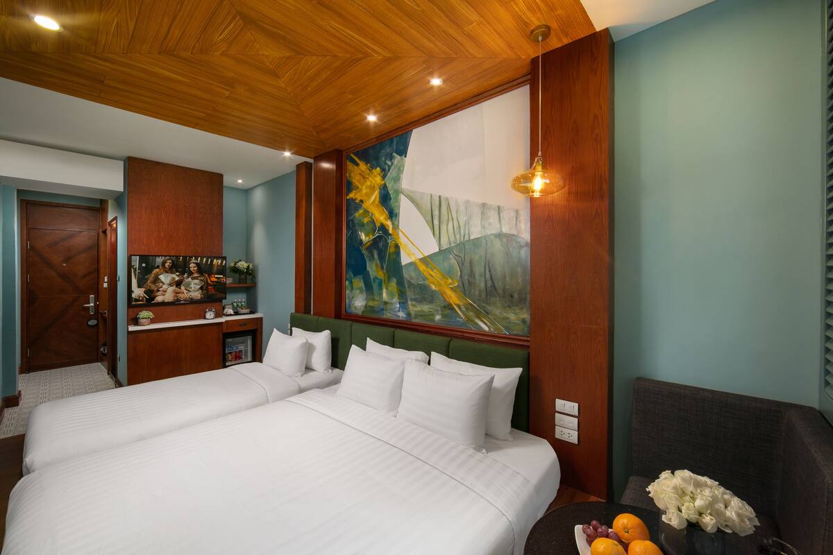 A hotel room with a large bed, a desk with a computer, a painting on the wall, and a view of the outdoors.