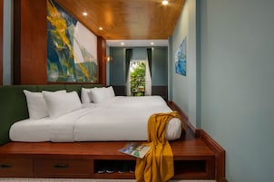 A bedroom with a bed, a green sofa, a wooden bench, and a magazine on the bench.