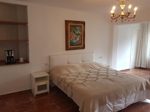 A bedroom with a bed, a nightstand, a coffee maker, a painting, and a chandelier. - Valentino Bed & Breakfast (Fuengirola)