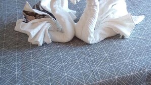 A bed with a geometric patterned bedspread and two swan-shaped towels on it. - Valentino Bed & Breakfast (Fuengirola)
