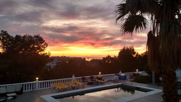 A pool area with lounge chairs and a view of the sunset. - Valentino Bed & Breakfast (Fuengirola)
