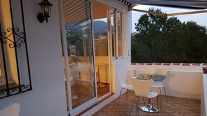 A balcony with a glass door, white chairs, a small table, and a metal lantern. - Valentino Bed & Breakfast (Fuengirola)