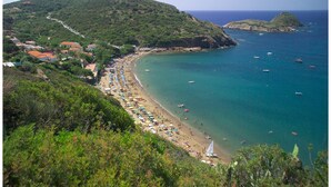 A coastal beach with a long stretch of beach, numerous umbrellas, and boats in the water. - Villaggio Innamorata - Villa Quintavalle (Capoliveri)