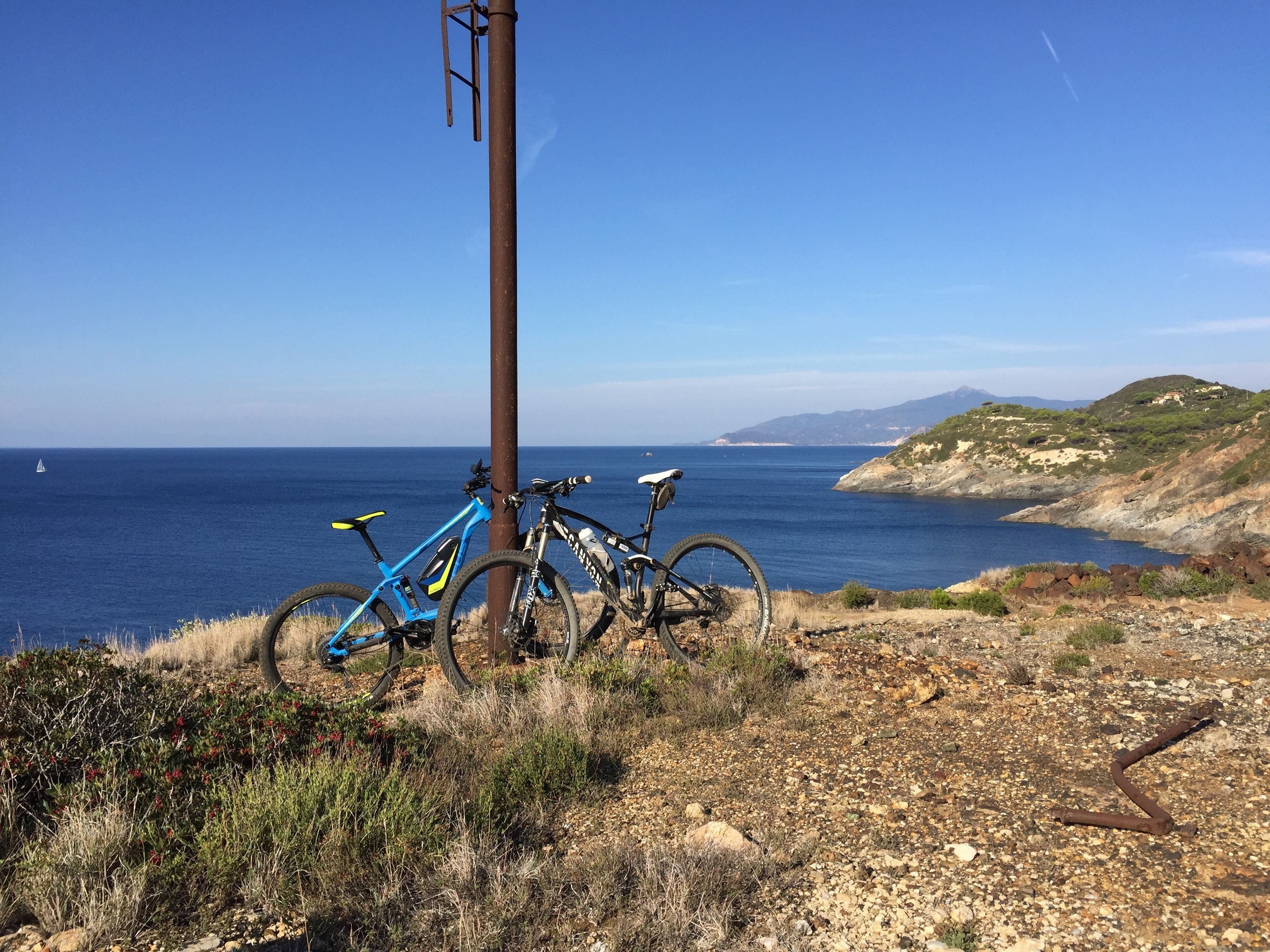 A coastal landscape with two bicycles parked against a utility pole, overlooking the sea.