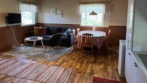 A cozy living room with a wooden ceiling, a sofa, a coffee table, and a dining table with chairs. - Salkolahti Minttu (Orivesi)