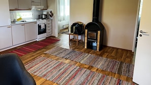 A compact kitchen with white cabinets, a stove, and a black wood-burning stove. - Salkolahti Minttu (Orivesi)