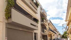 Una hilera de edificios modernos con balcones, algunos con plantas, y un cielo despejado.
