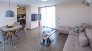 Una sala de estar moderna con comedor, sofá y televisor.