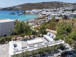 A coastal town with white buildings, a beach, and a view of boats on the water. - MyMykonos Villa (Mykonos)