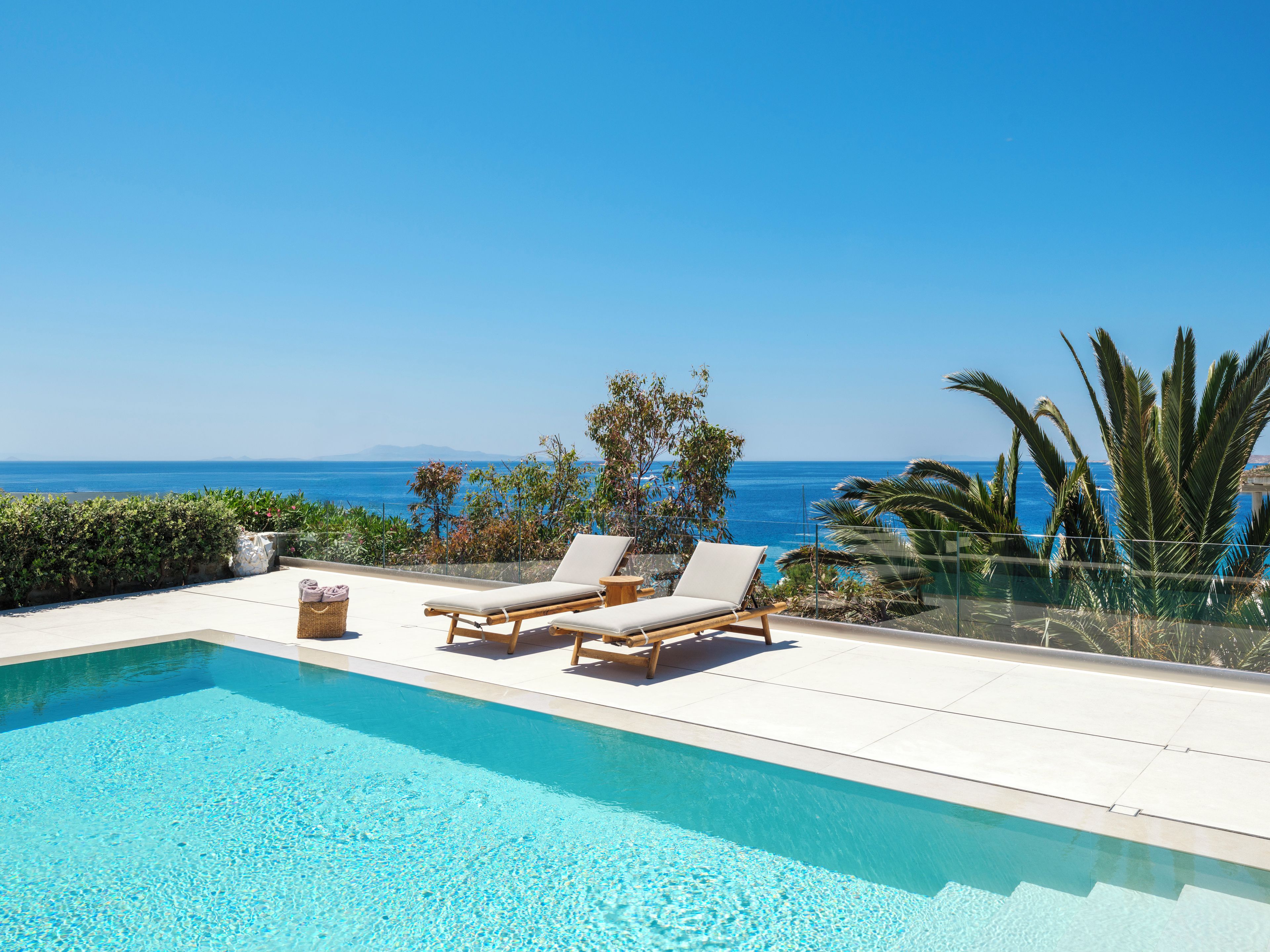 A pool with lounge chairs and a view of the ocean.