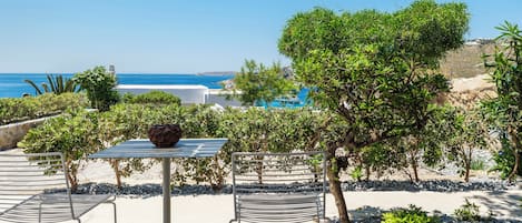 Un espace extérieur aménagé avec une table et des chaises, un vase décoratif, et une vue sur la mer et les bâtiments en arrière-plan.