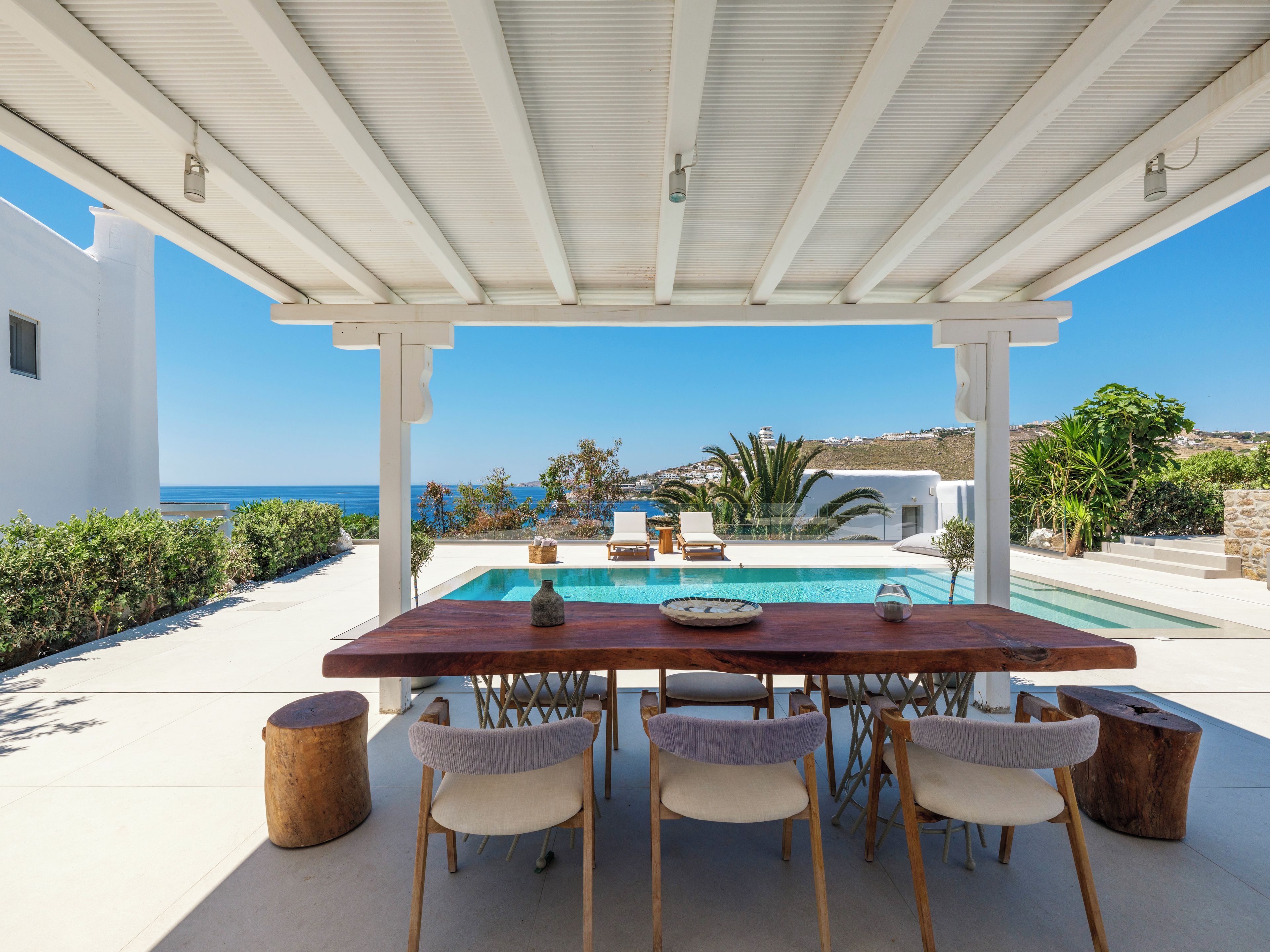 Un espace extérieur abrité, doté d’une piscine, de murs blancs et offrant une vue sur la mer.