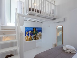 A bedroom with a bed, a painting, a staircase, and a mirror. - myMykonos Villa 1 (Mykonos)