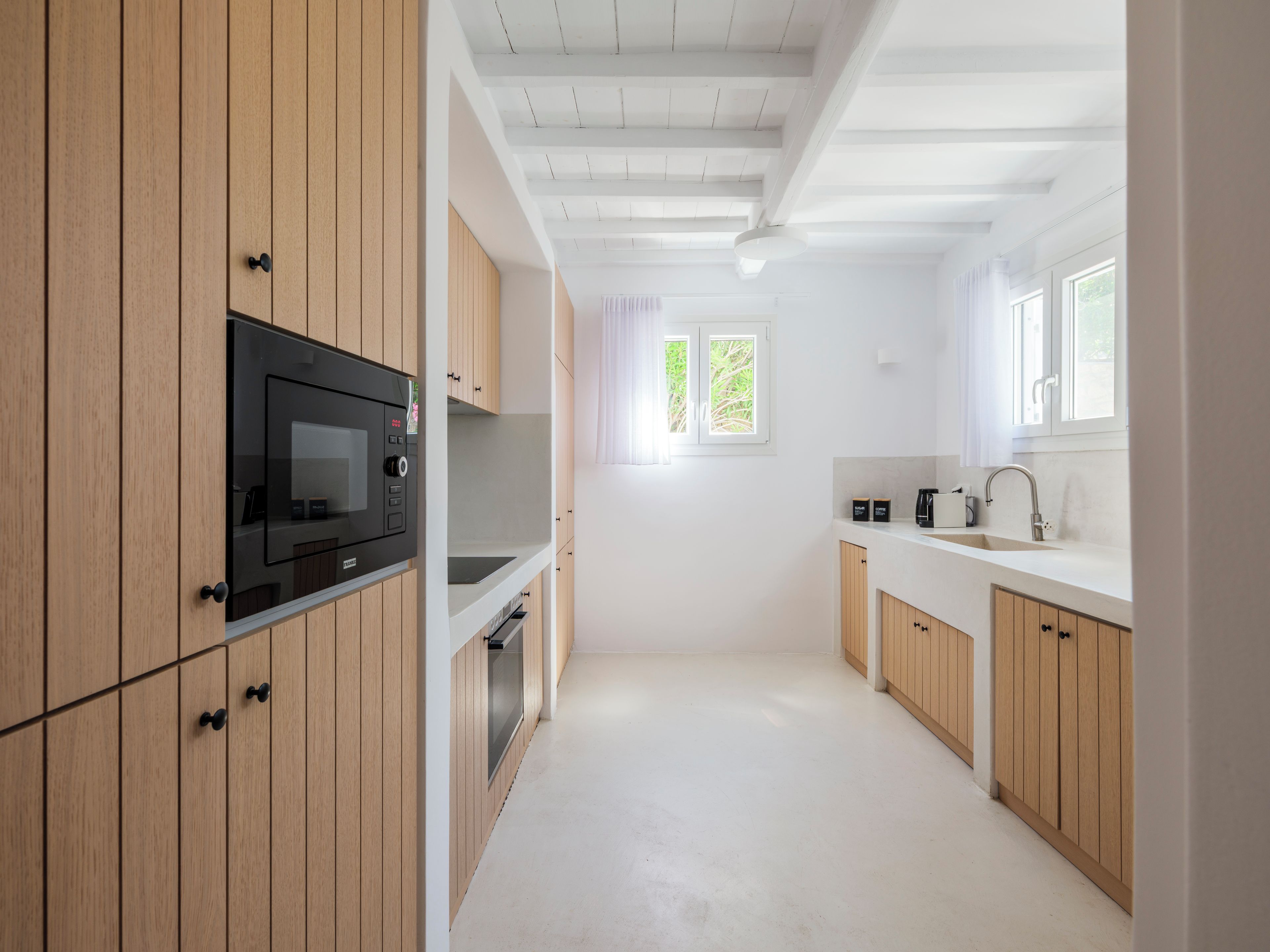 Eine moderne Küche mit Holzschränken, einer integrierten Mikrowelle und einem Fenster für natürliches Licht.