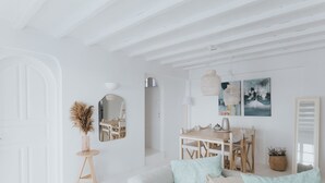 A minimalist living room with a white sofa, a dining table, and a mirror. - MyMykonos Villa (Mykonos)