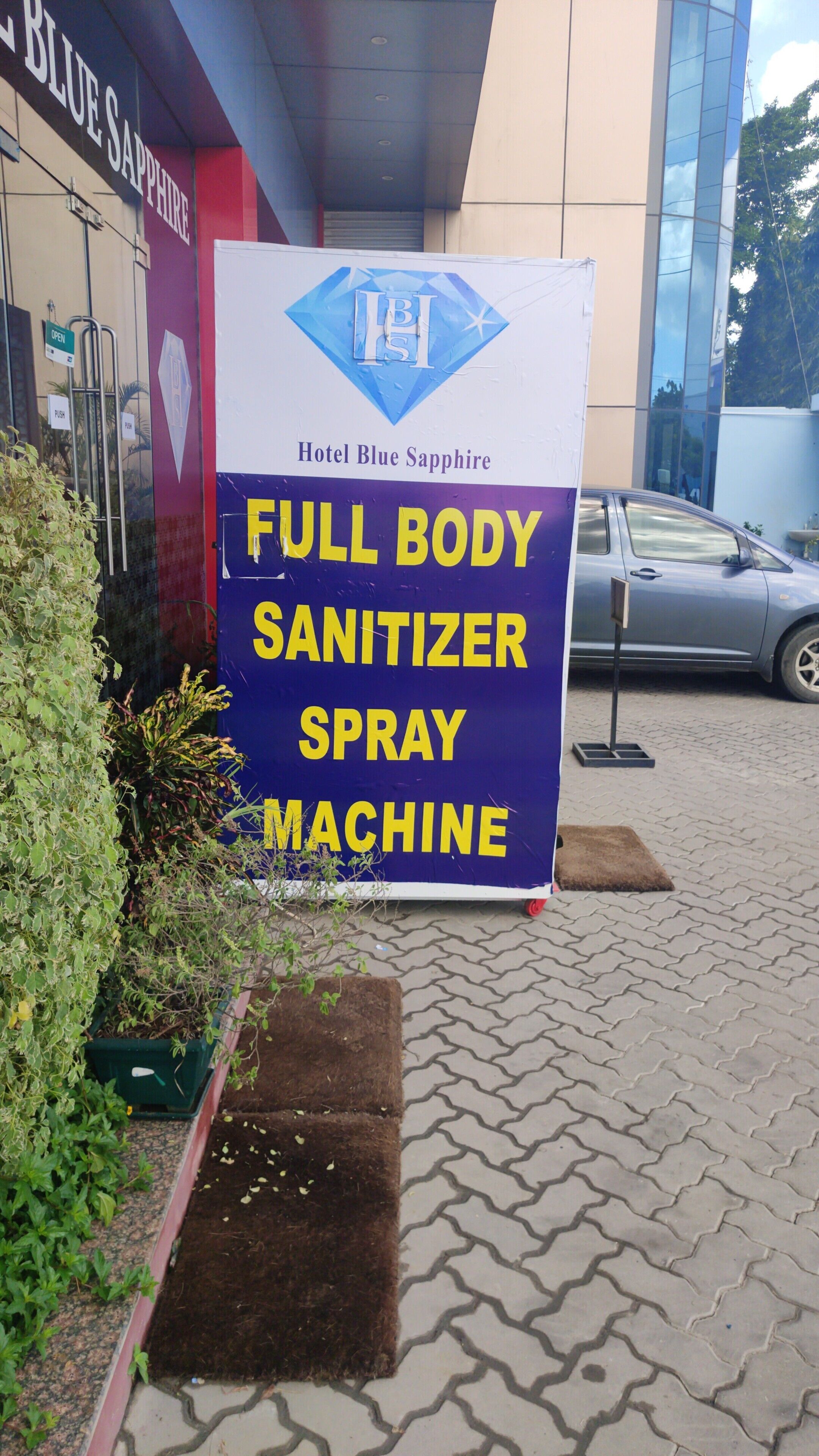 A sign for a full body sanitizer spray machine outside Hotel Blue Sapphire.